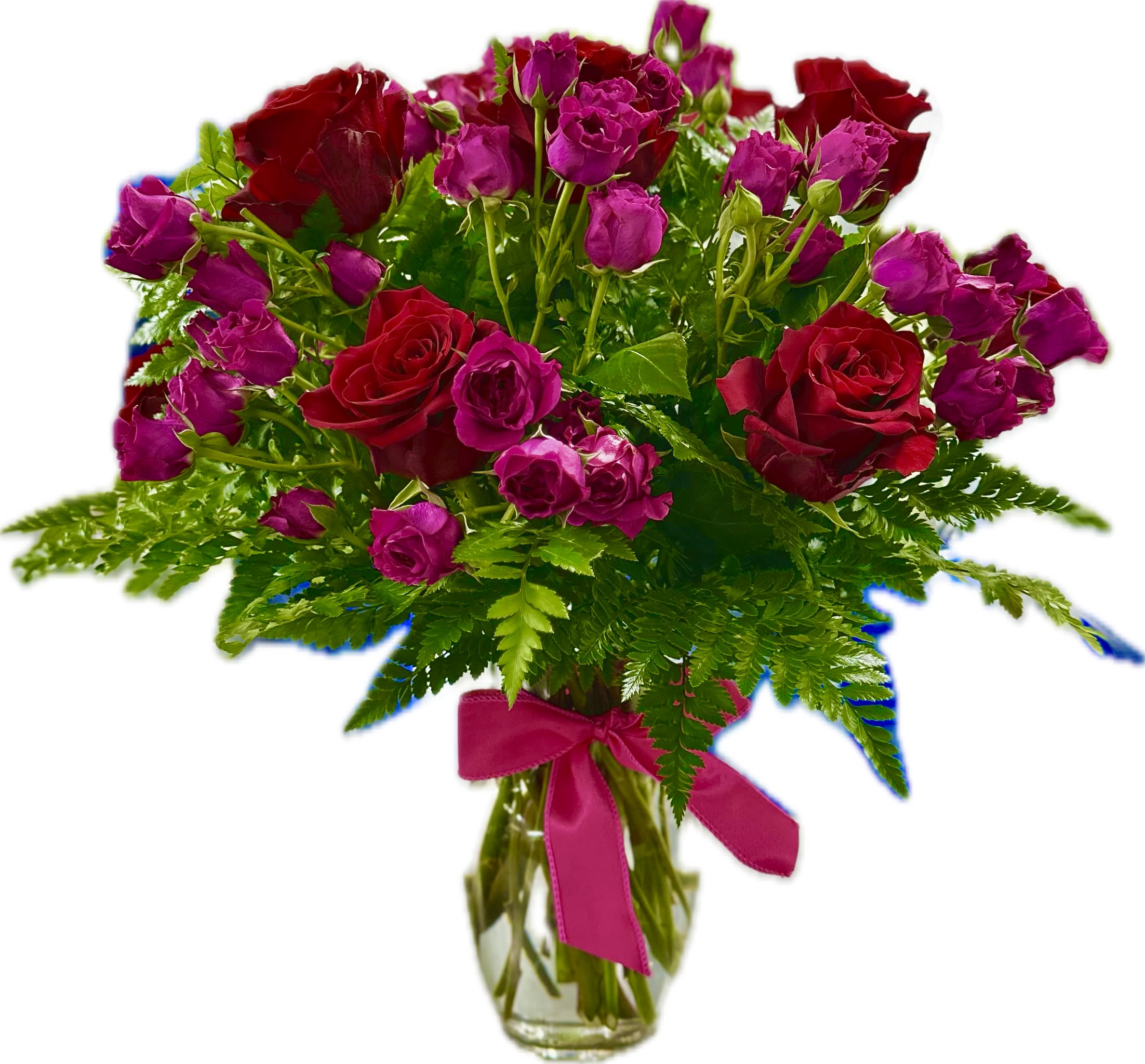Red roses and pink spray roses in a glass vase with a ribbon