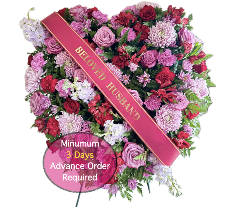 Heart-shaped floral tribute with a "Beloved Husband" sash