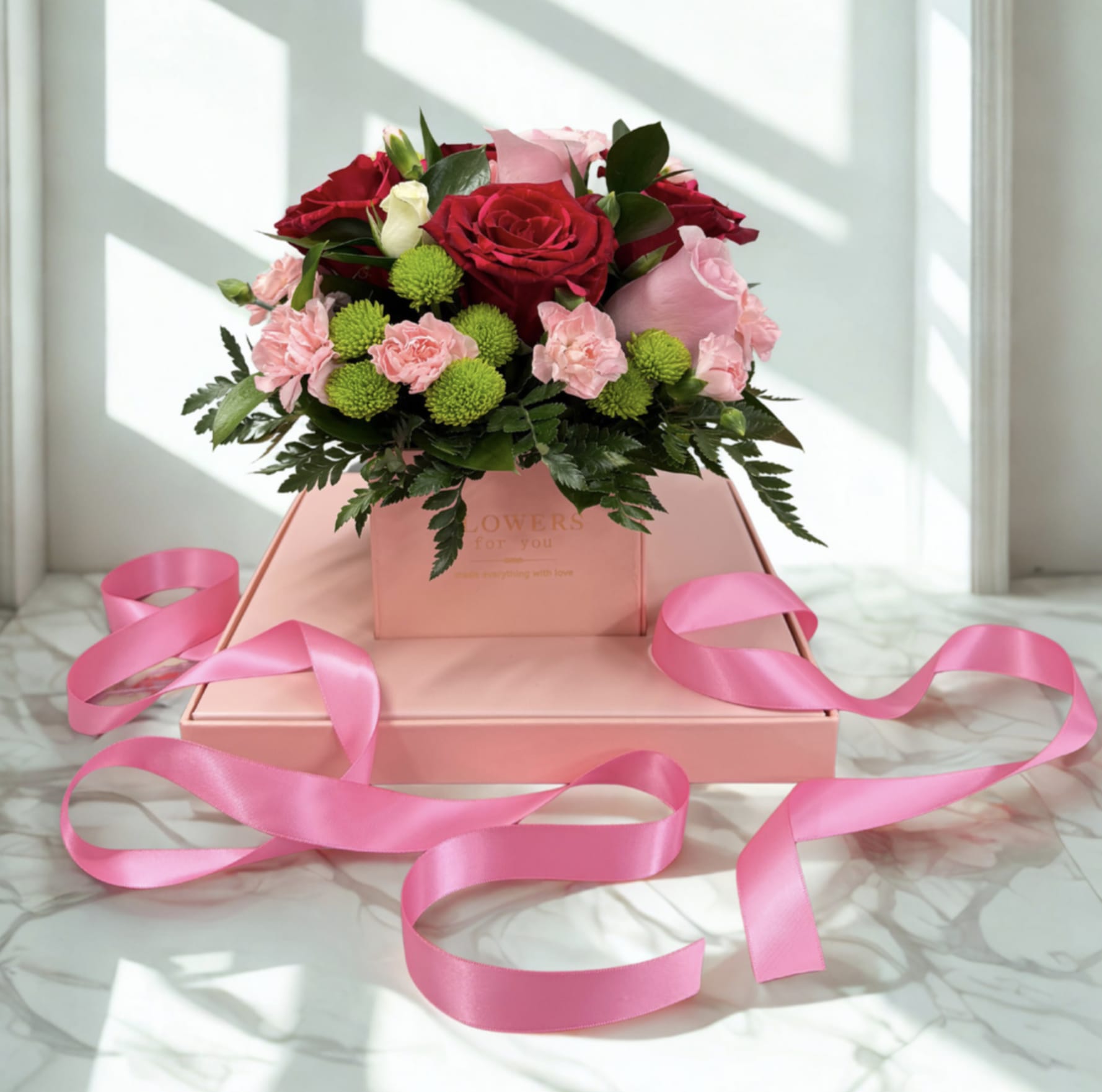 Pink and red rose bouquet in a pink gift box with ribbon
