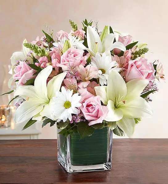 Pink roses and white lilies arranged in a square glass vase