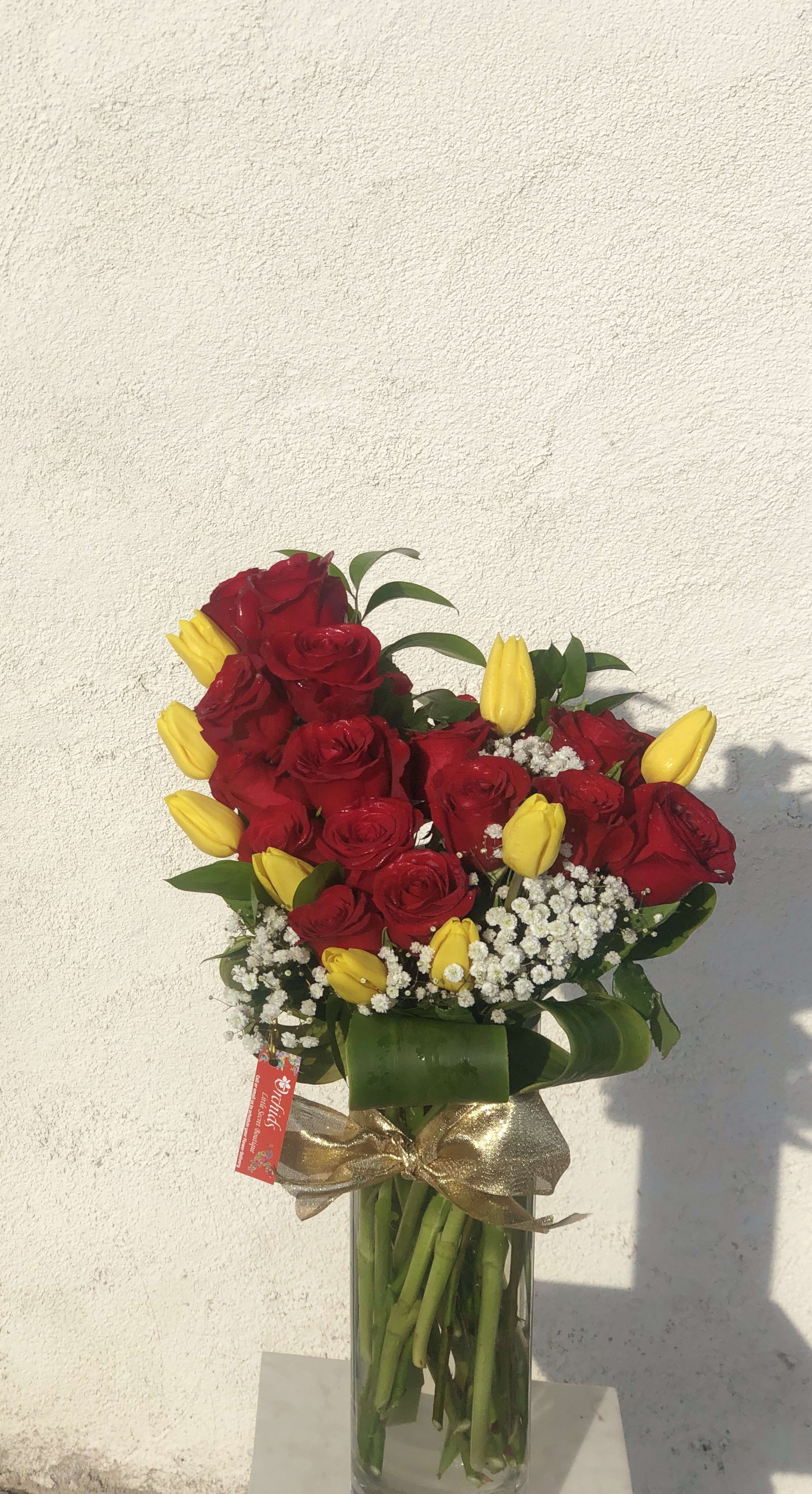 Bouquet of red roses and yellow tulips in a glass vase