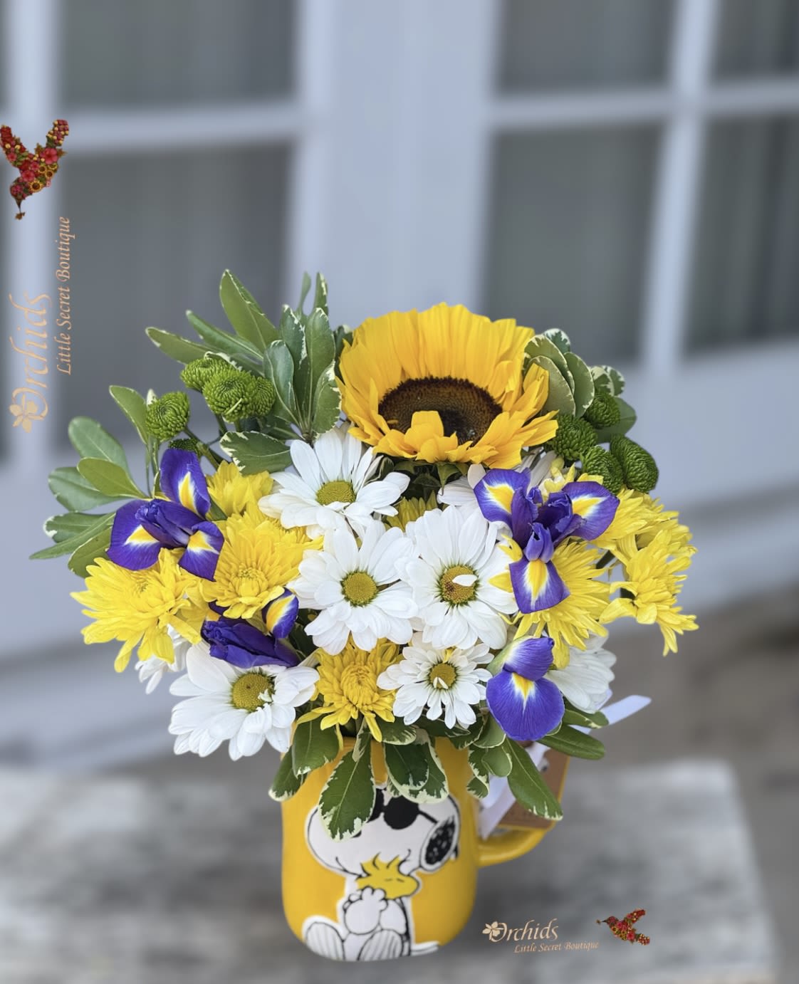 Bouquet of yellow, white, and purple flowers in a Snoopy mug