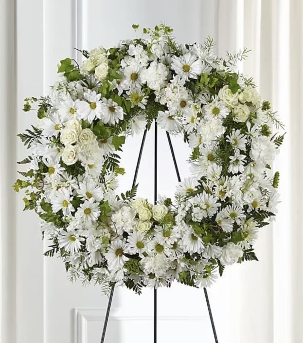 White floral wreath on a black easel stand