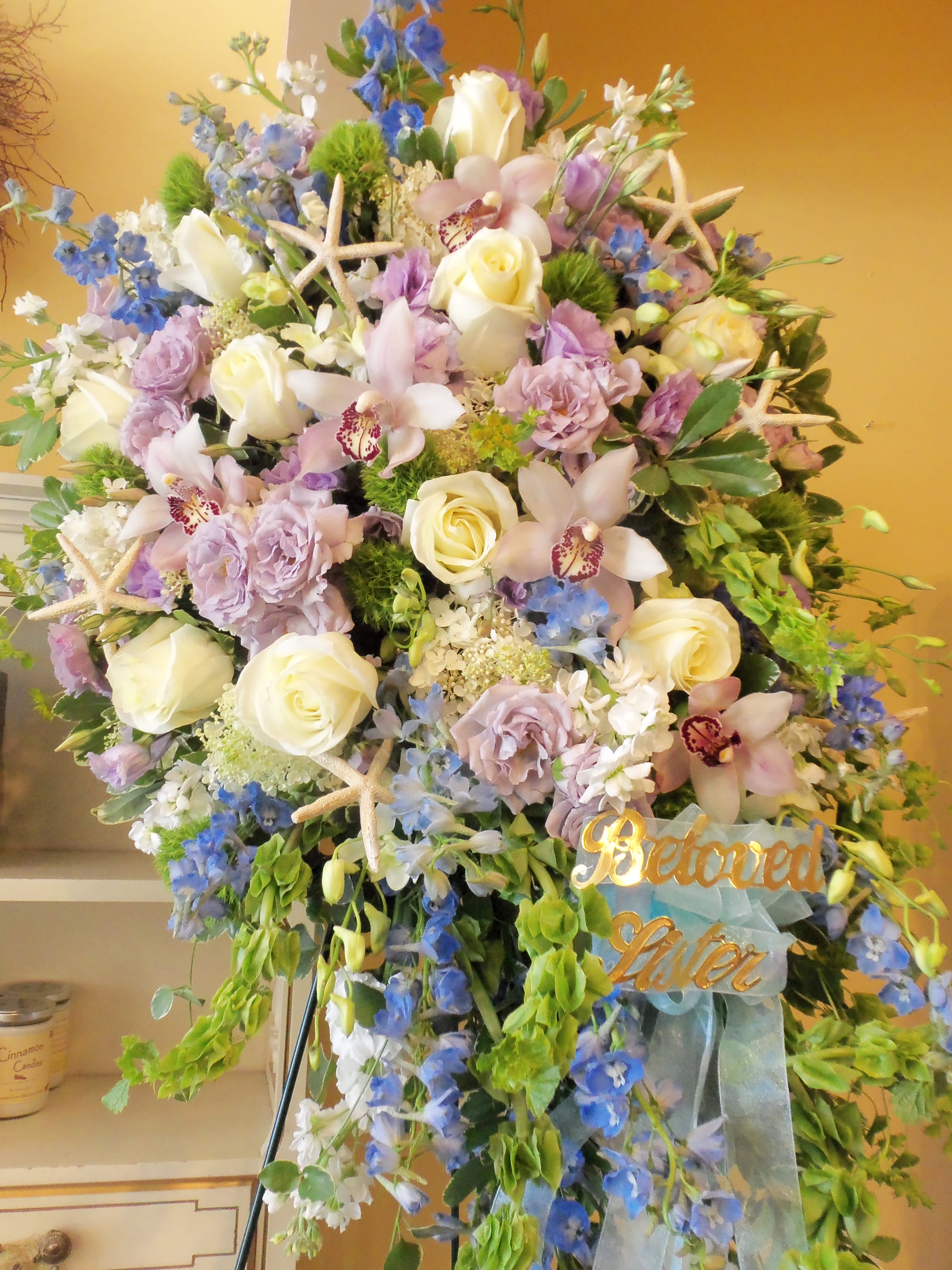 Large pastel floral standing spray with roses, orchids, and blue flowers
