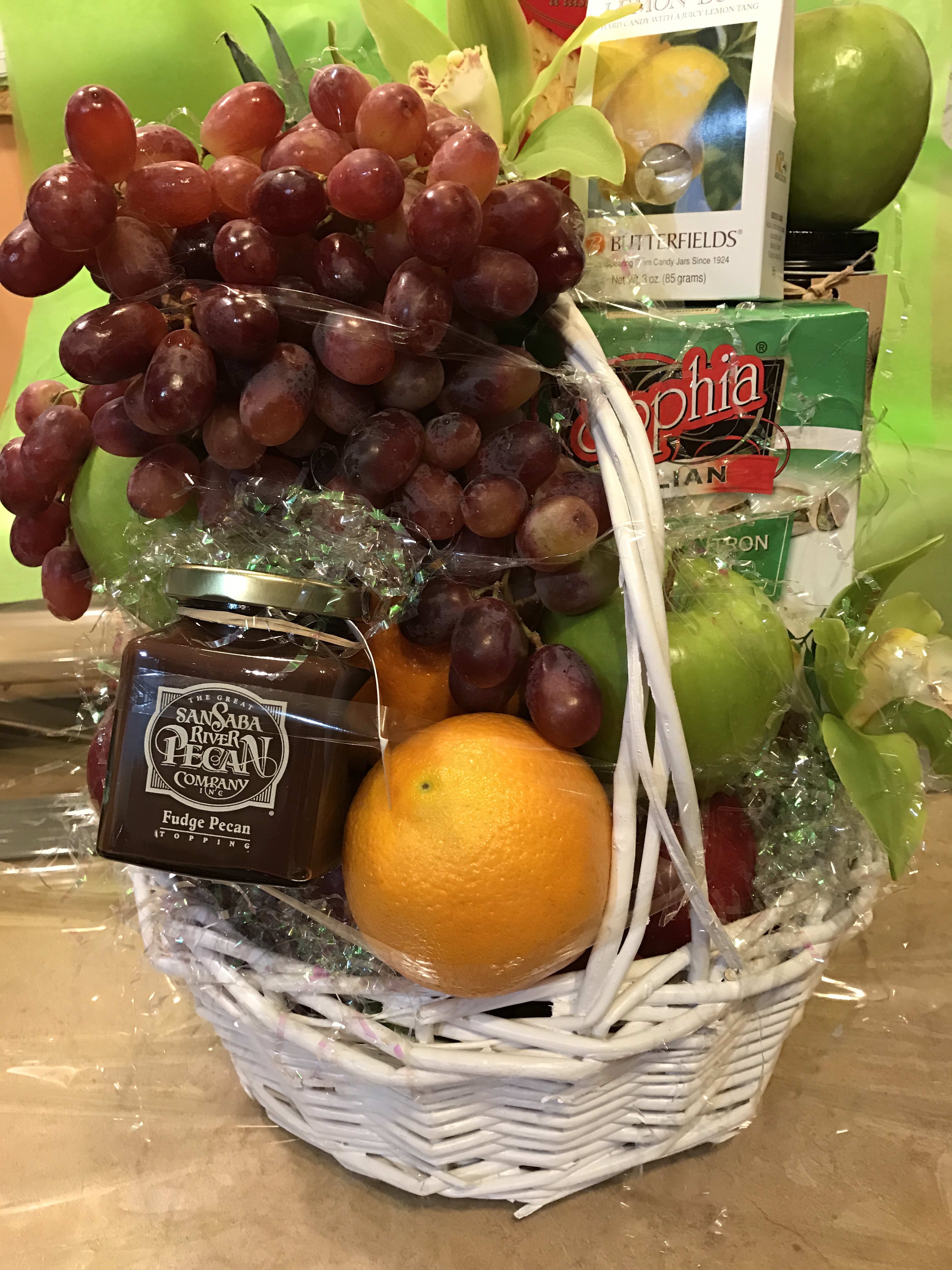Gift basket with grapes, oranges, candy, and a white wicker basket