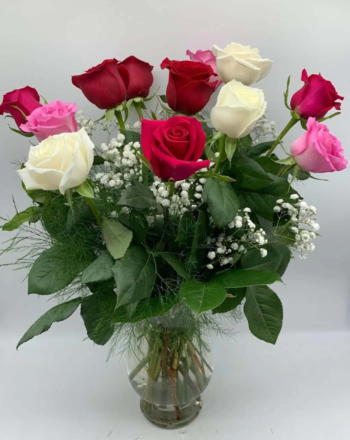 Bouquet of red, pink, and white roses in a clear glass vase
