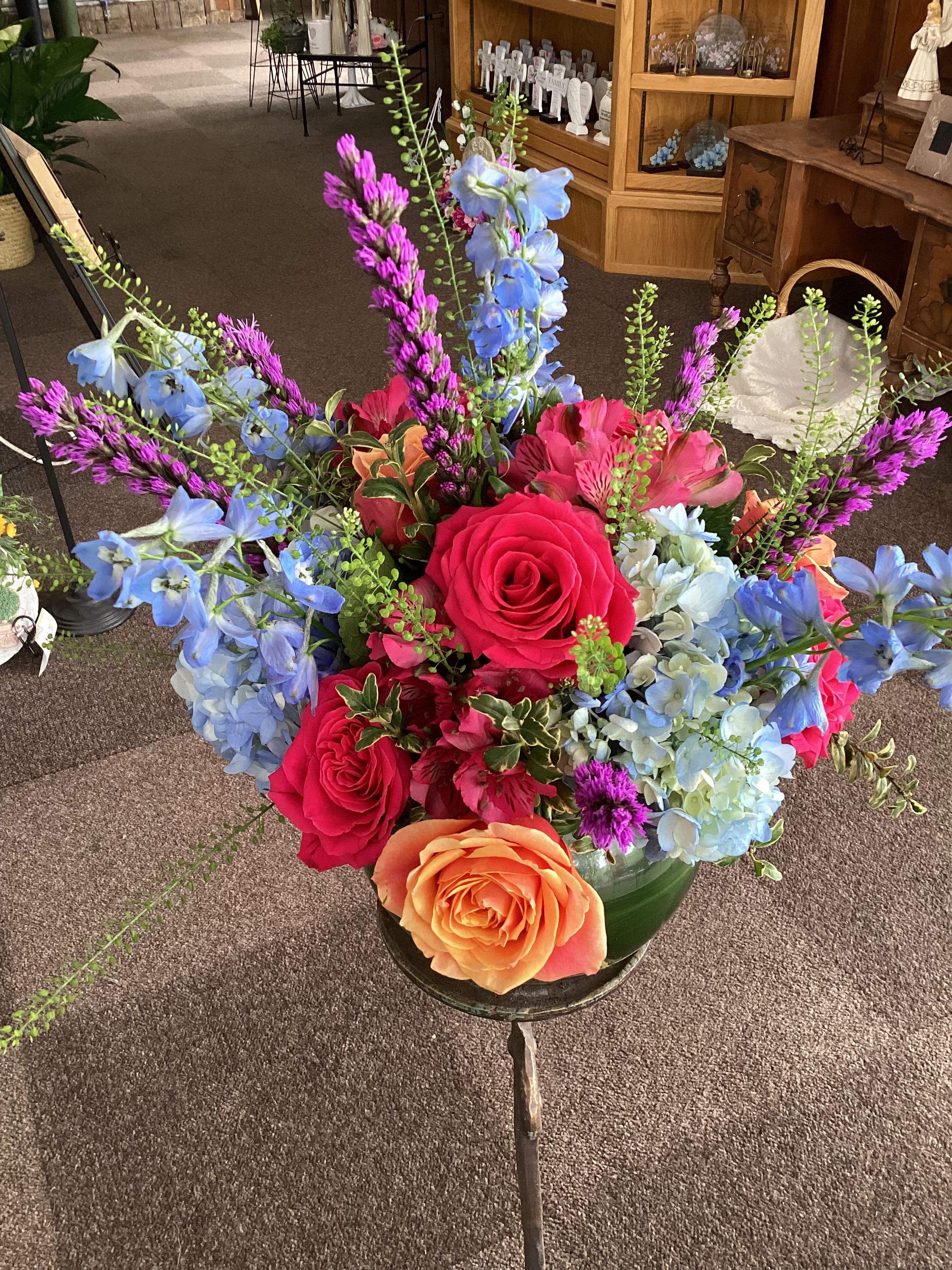Lavish Birthday Bowl - Stunning mix of pale blue hydrangeas, sky blue delphinium, hot pink and cherry brandy roses, magenta liatris and an ever changing mix of other flowers make this a stunning birthday gift arranged in a leaf lined 8” bubble bowl. 