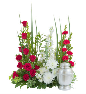 Red roses and white flowers arranged beside a silver urn