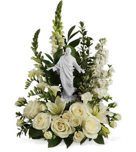 White floral arrangement with a small statue of Jesus in the center