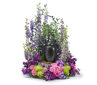 Purple and pink floral arrangement around a black urn