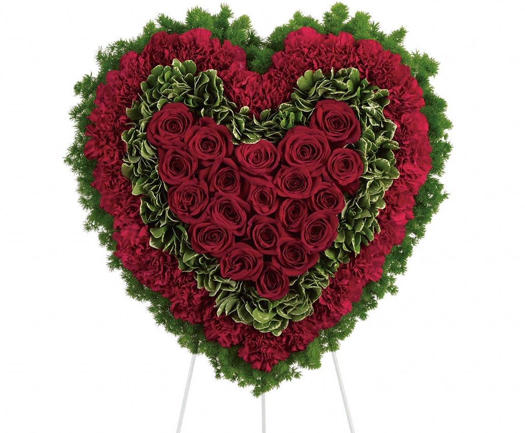 Heart-shaped floral tribute with red roses and carnations on a stand