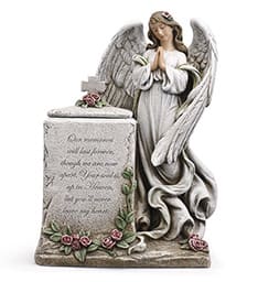 Angel statue beside a memorial stone with small pink roses