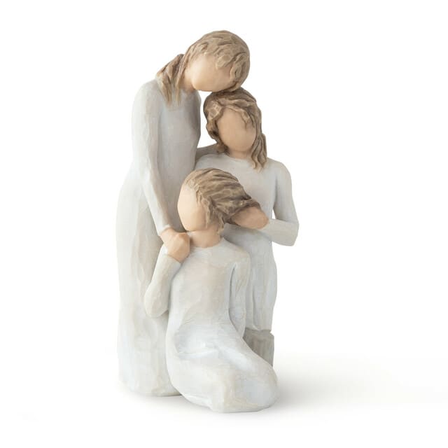 Three faceless figurines in white dresses posed closely together