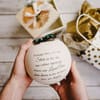 Hands holding a round white gift box with a printed message