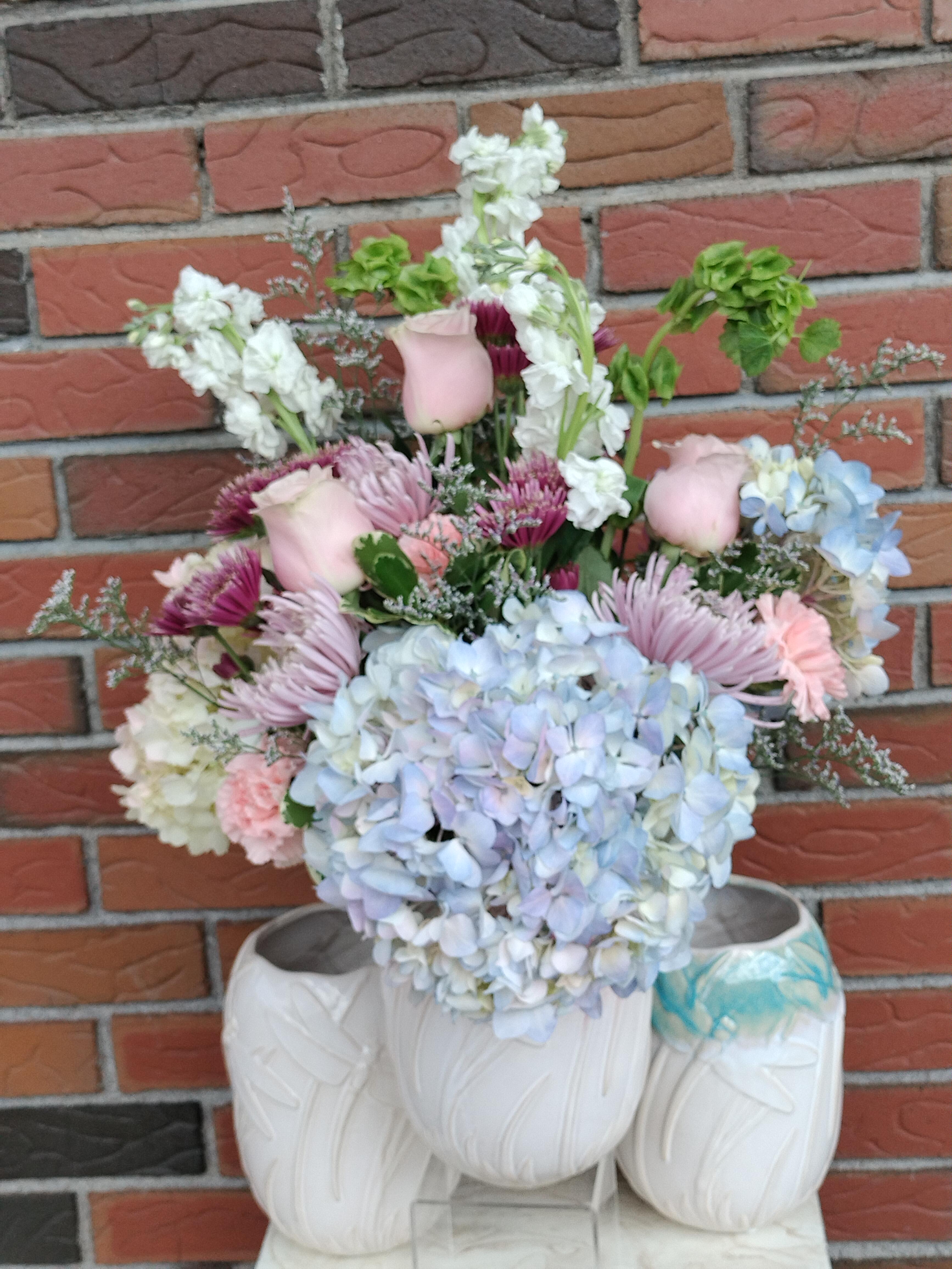 Pastel bouquet with hydrangeas, roses, and chrysanthemums in white vases