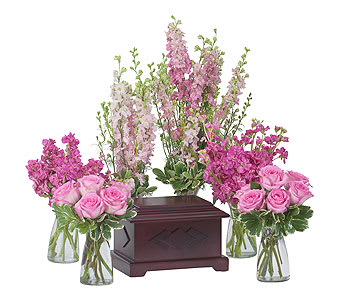 Pink rose bouquets and tall pink floral sprays around a wooden urn