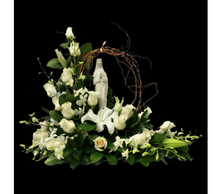 White floral arrangement with lilies and roses around a religious statue