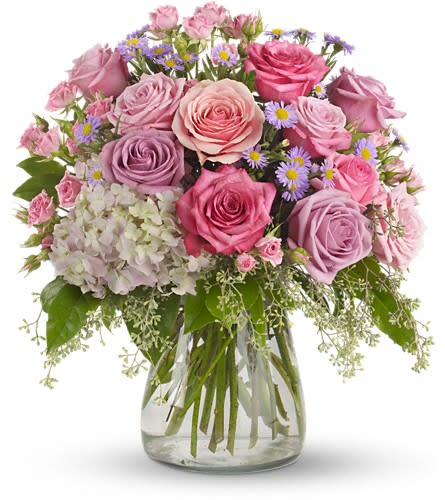 Pink and lavender roses in a glass vase with small purple flowers