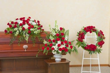 Red carnation funeral arrangements on a casket and wreath stand