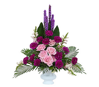 Pink roses and purple flowers arranged in a white vase