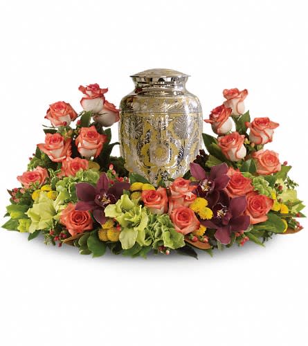 Coral roses arranged around a silver urn centerpiece