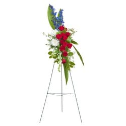 Tall floral spray with red roses, white blooms, and blue accents on a stand