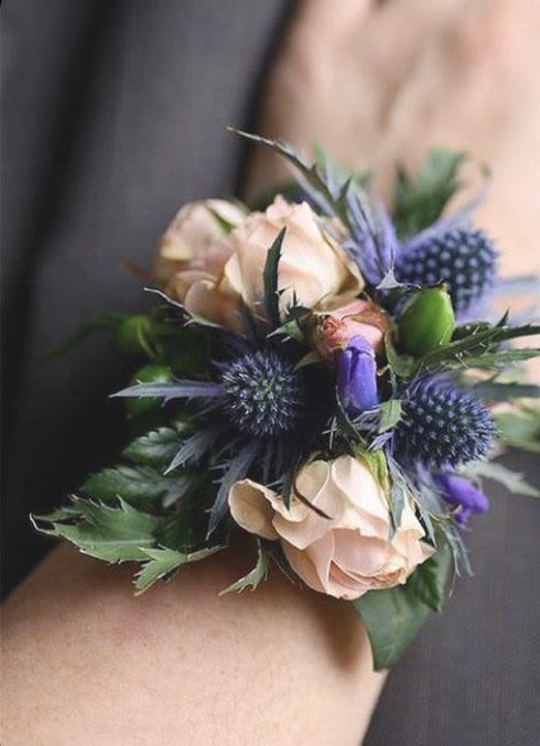 Small wrist corsage with pale roses and blue thistle-like flowers