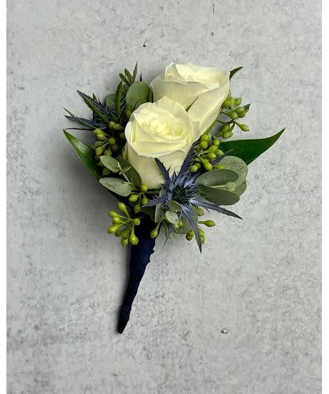White rose boutonniere with blue-green foliage on a dark wrap