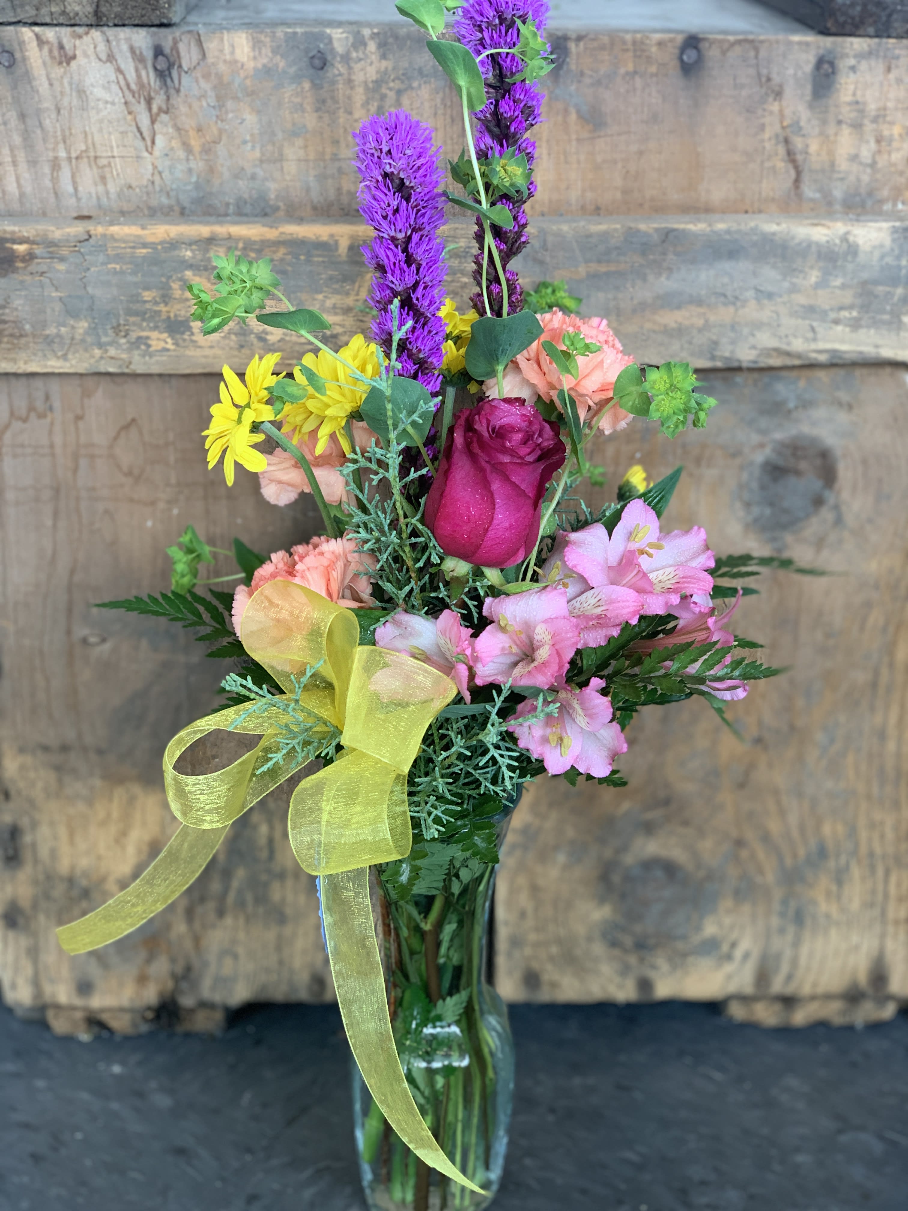 Mixed bouquet in a glass vase with pink, purple, and yellow flowers