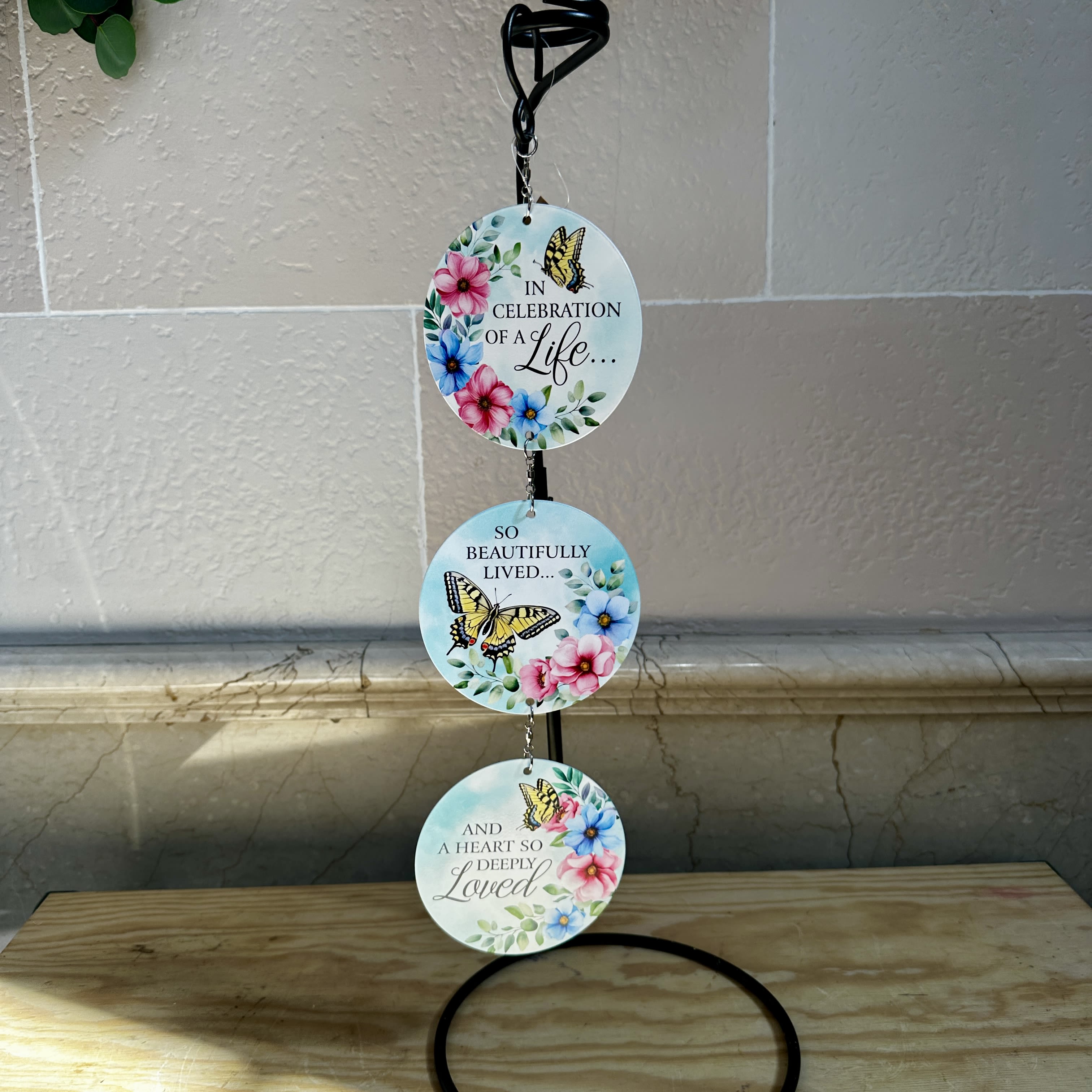 Three round memorial plaques with butterflies and flowers hang from a black stand.