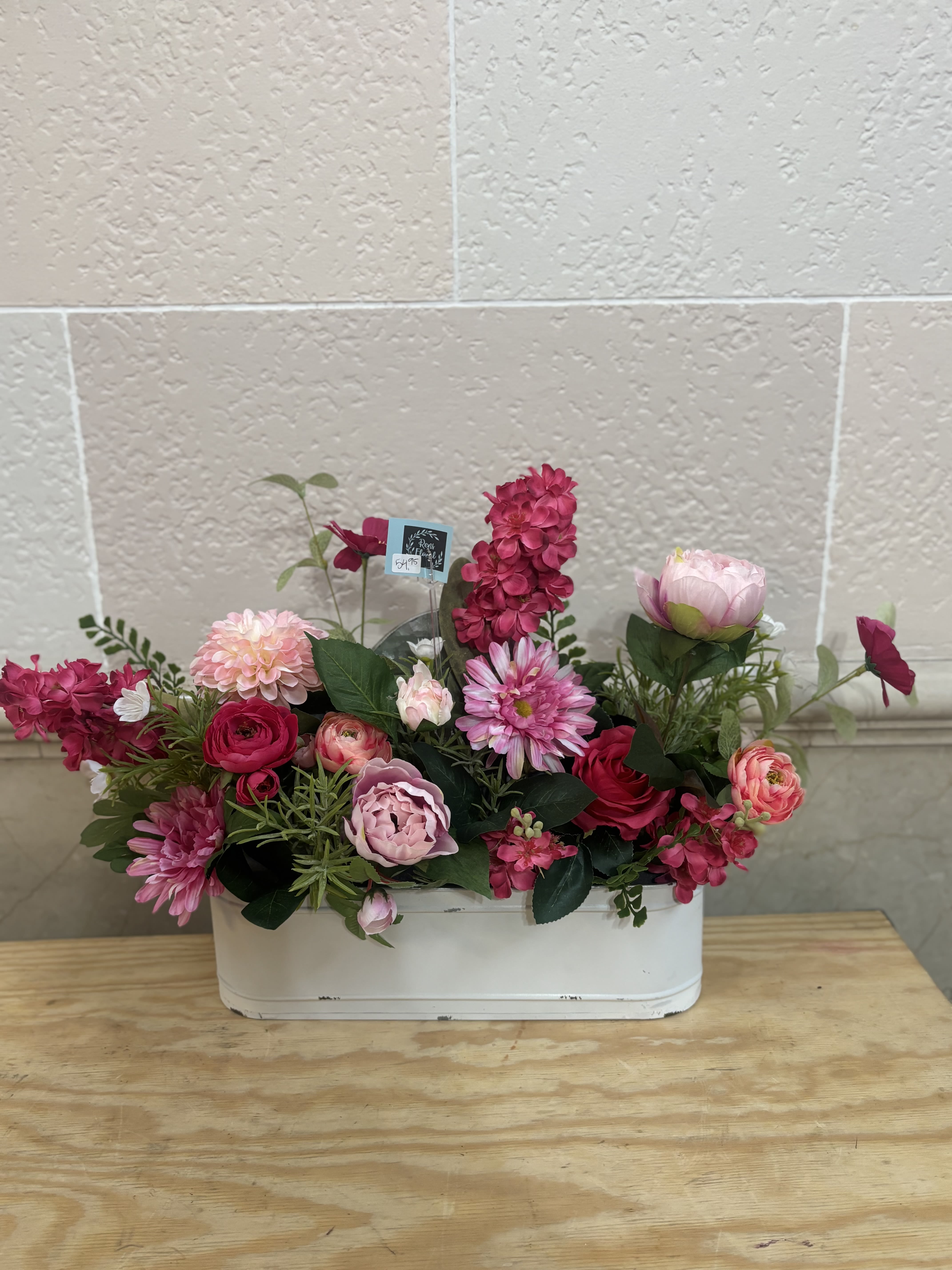 Pink and red mixed flower arrangement in a white container