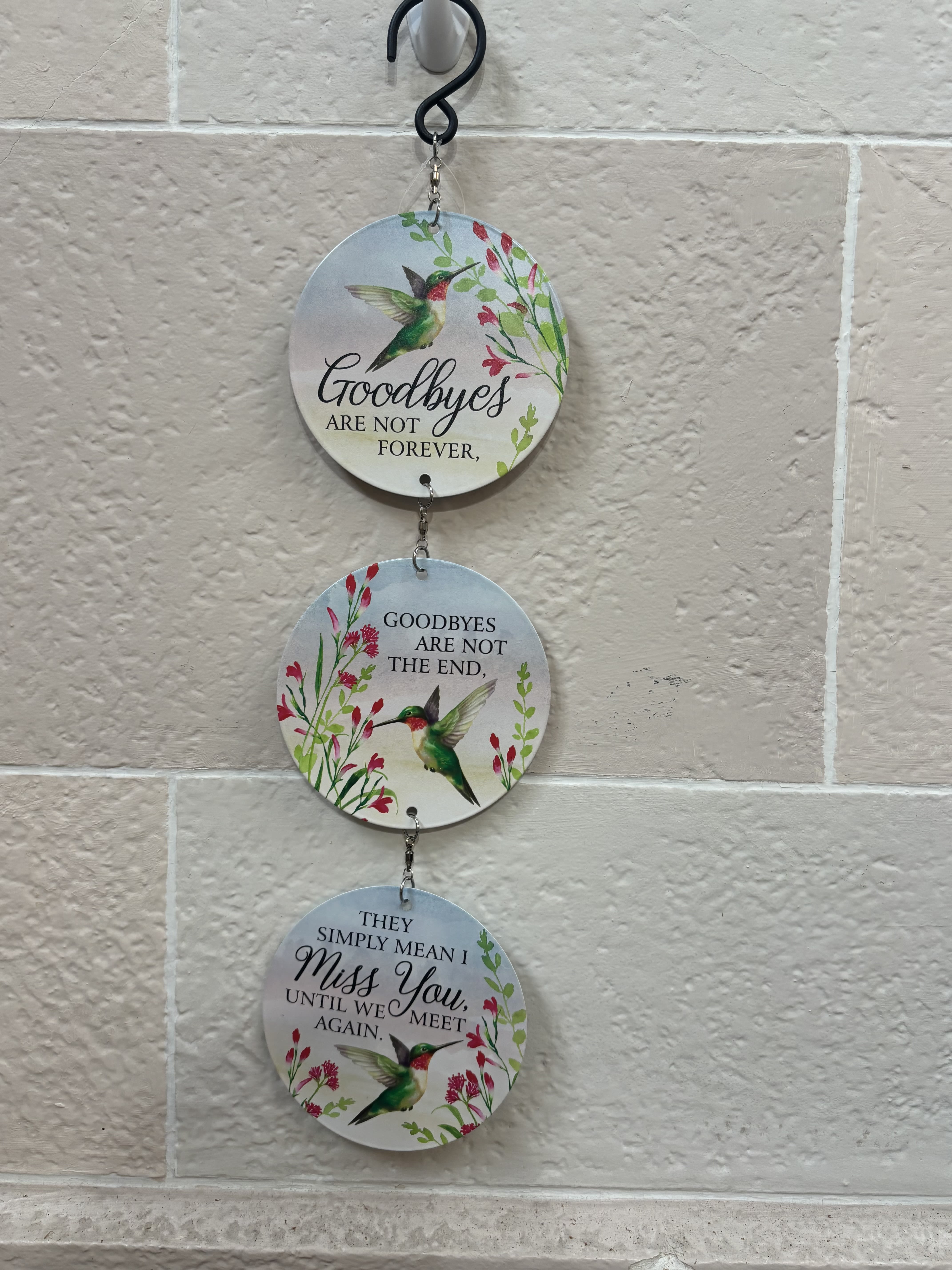 Three hanging round plaques with hummingbirds and floral designs on a wall.