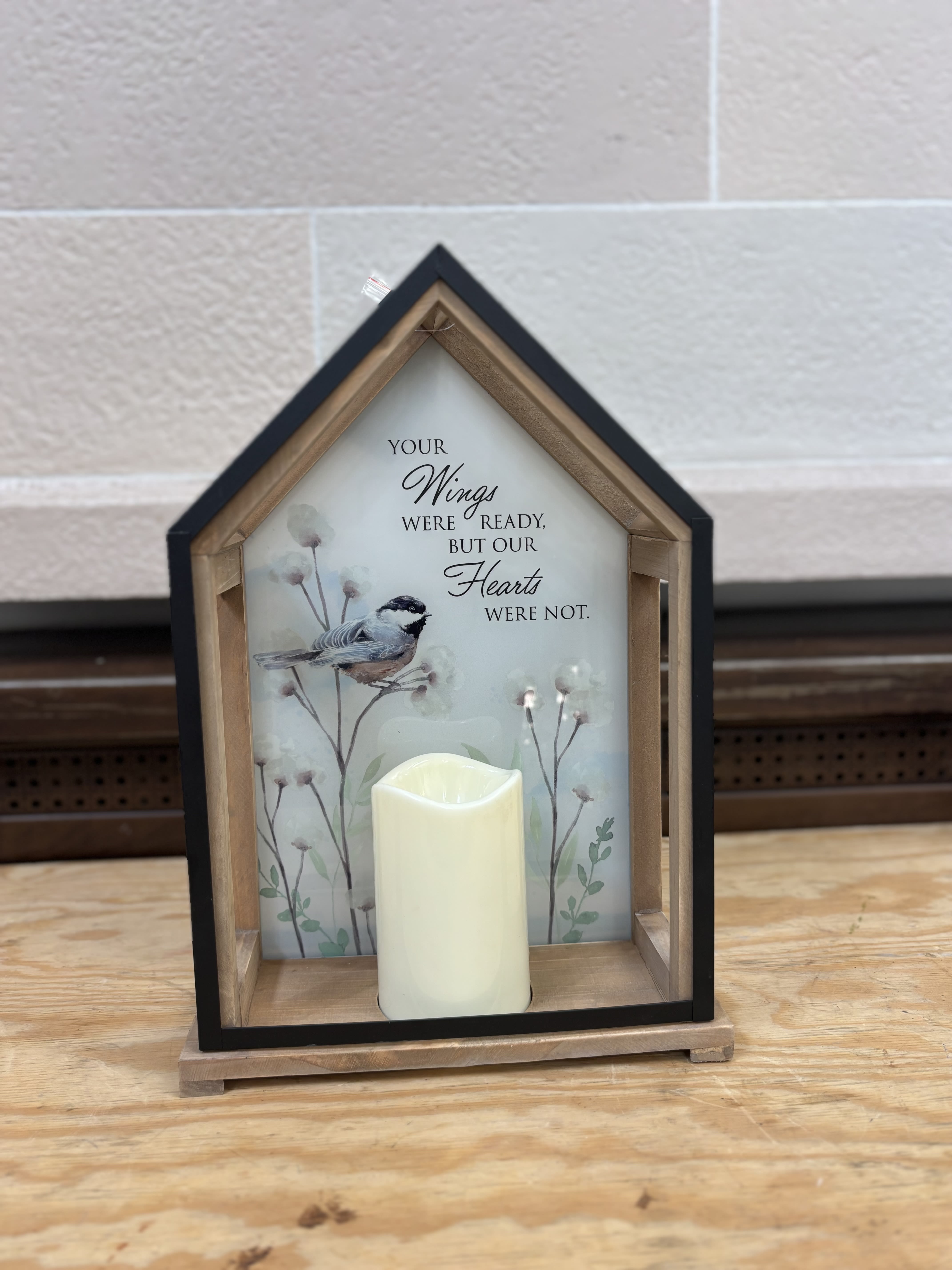 House-shaped memorial lantern with a candle and bird illustration