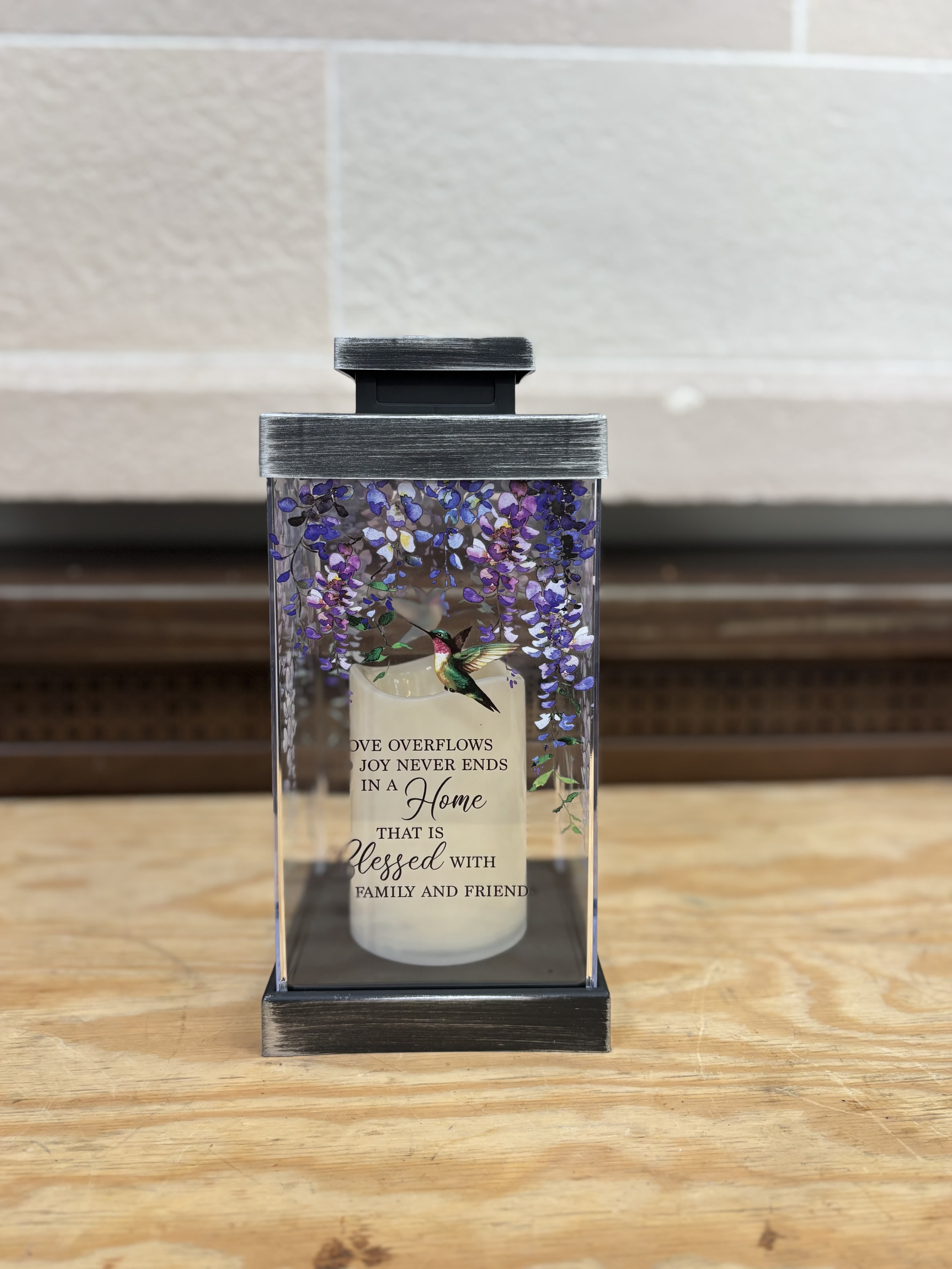 Decorative candle in a glass lantern with purple floral accents