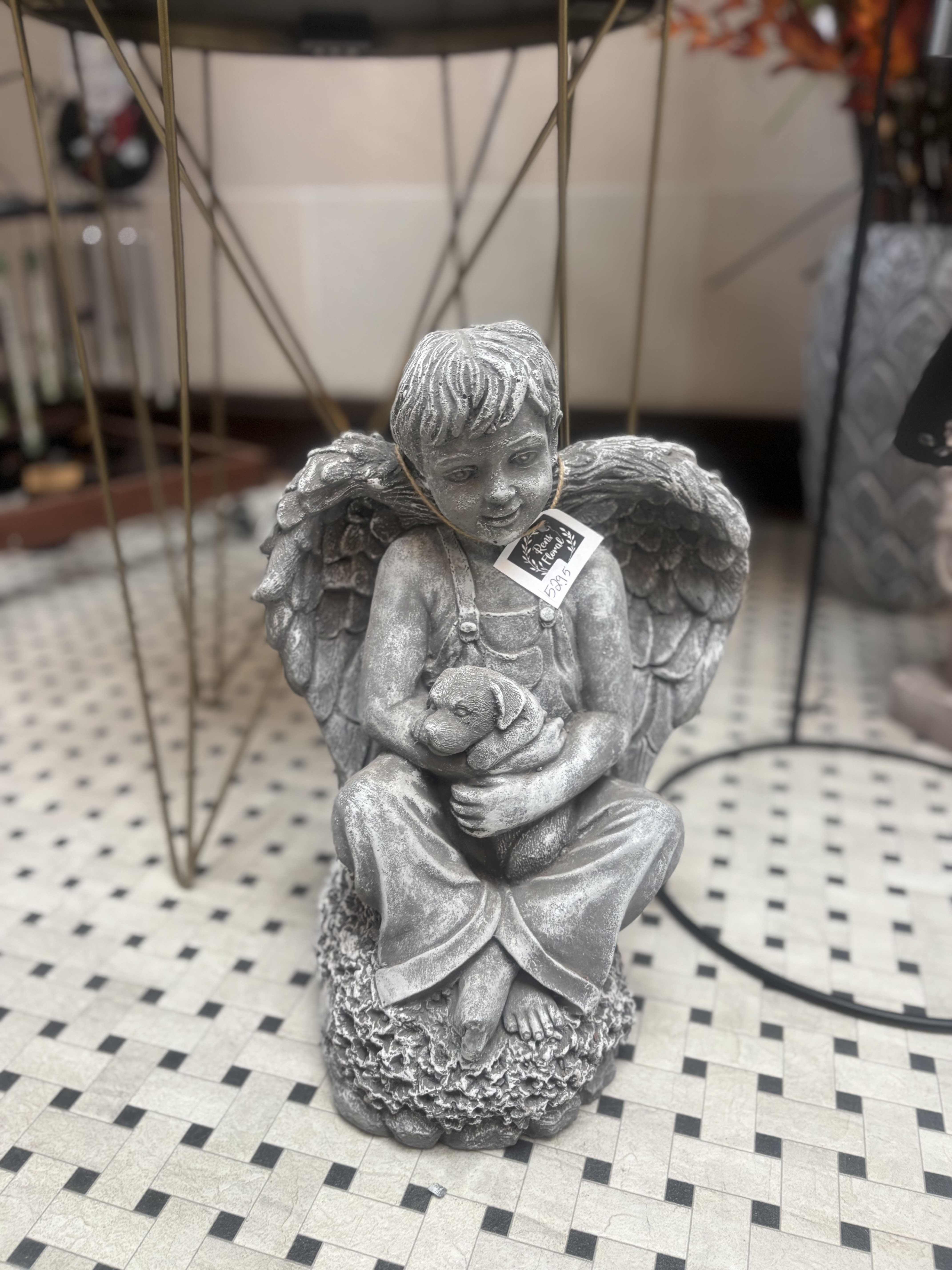 Gray angel statue holding a small dog figurine