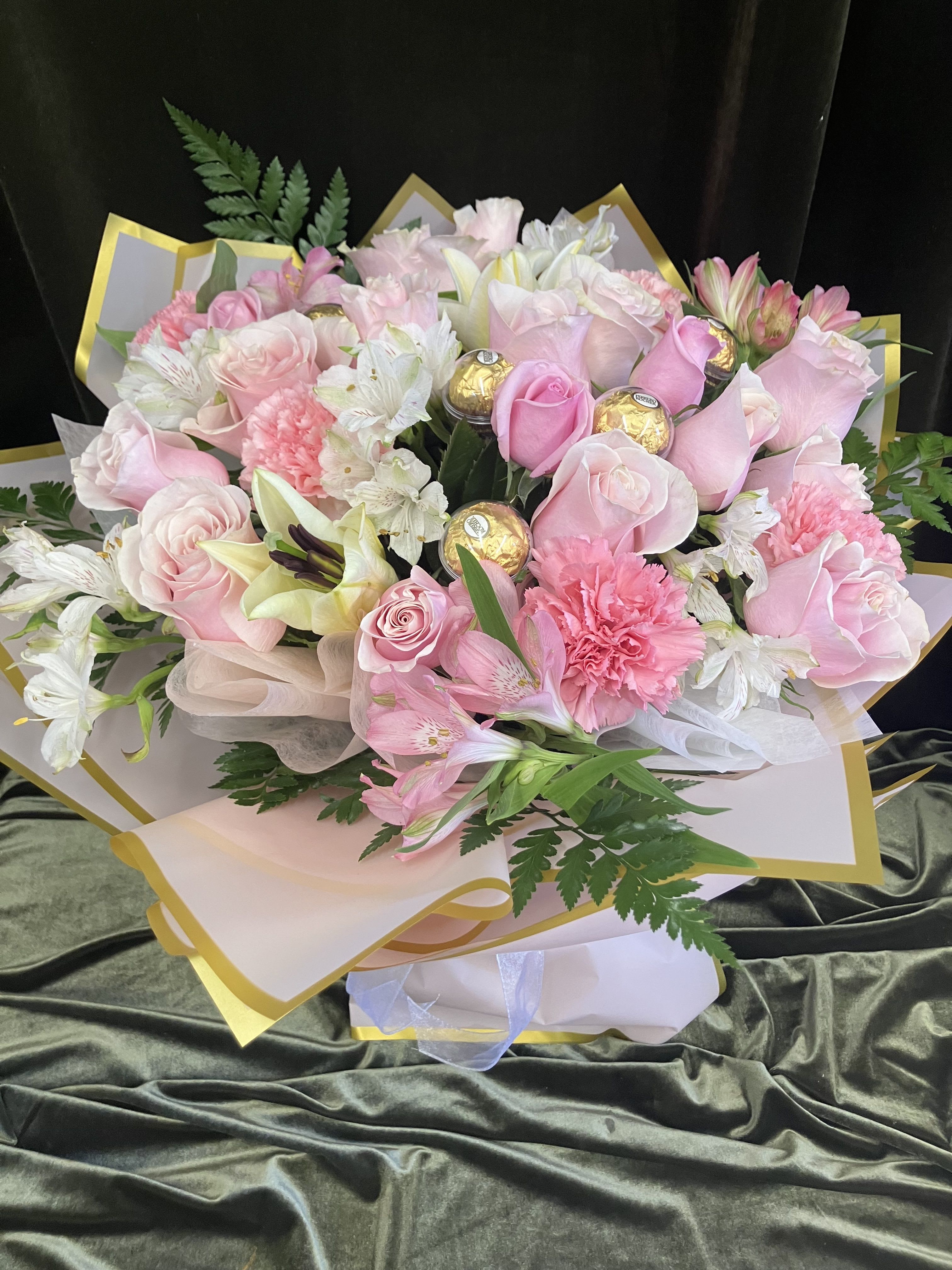 Pink and white bouquet with roses, lilies, and carnations wrapped in gold-trimmed paper