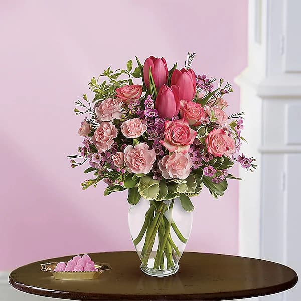 Pink tulips and roses arranged in a clear glass vase