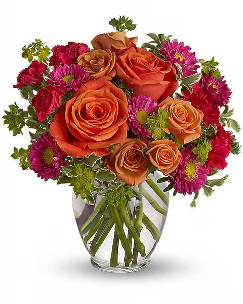 Orange roses and magenta daisies in a clear glass vase