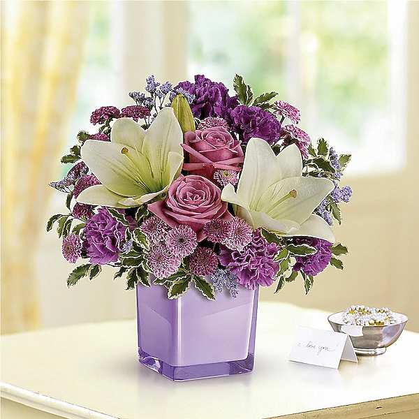Purple and pink bouquet with white lilies in a lavender vase