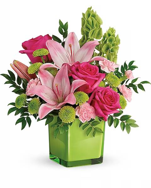 Pink lilies and roses arranged in a green square vase