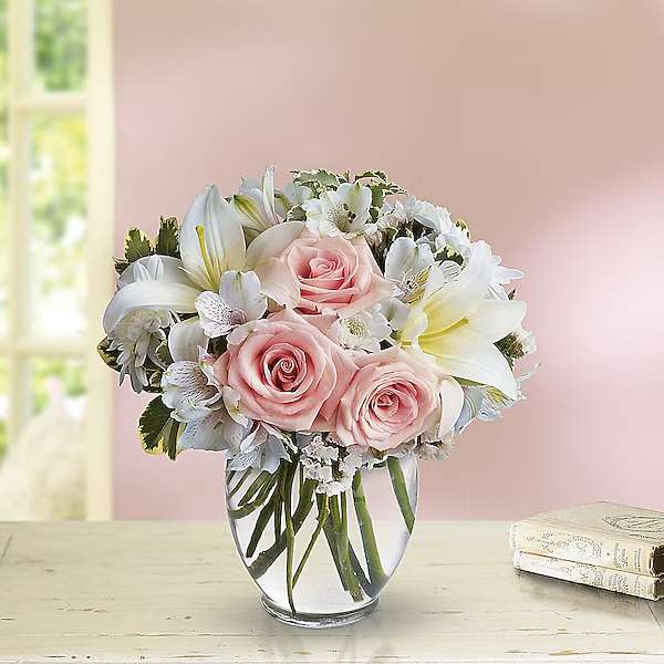 Pink roses and white lilies arranged in a clear glass vase