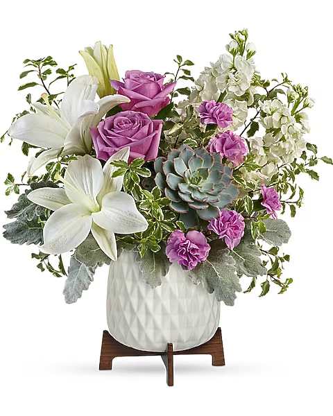 White lilies and purple roses arranged in a white vase with a succulent accent