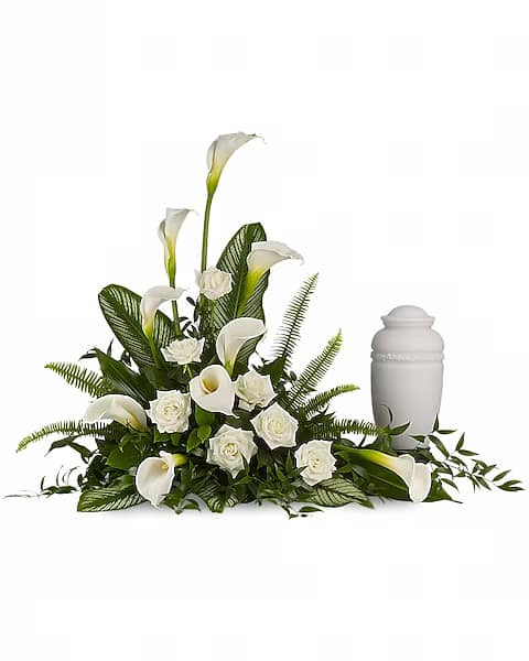 White calla lilies and roses arranged around a white urn