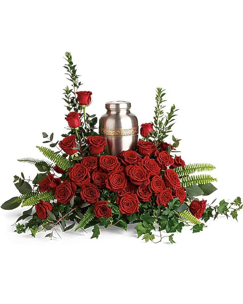 Red roses arranged around a silver urn with greenery