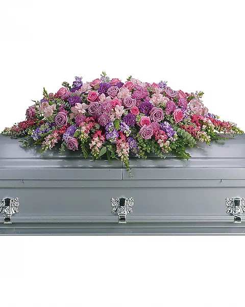 Large pink and purple floral casket spray on a gray casket