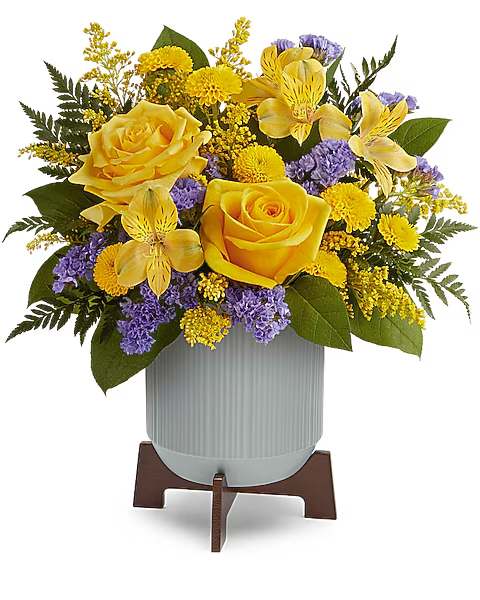 Yellow roses and purple flowers arranged in a vase on a stand