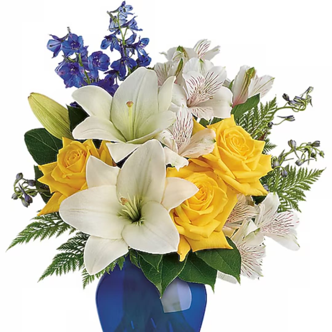 Bouquet of white lilies, yellow roses, and blue flowers in a blue vase