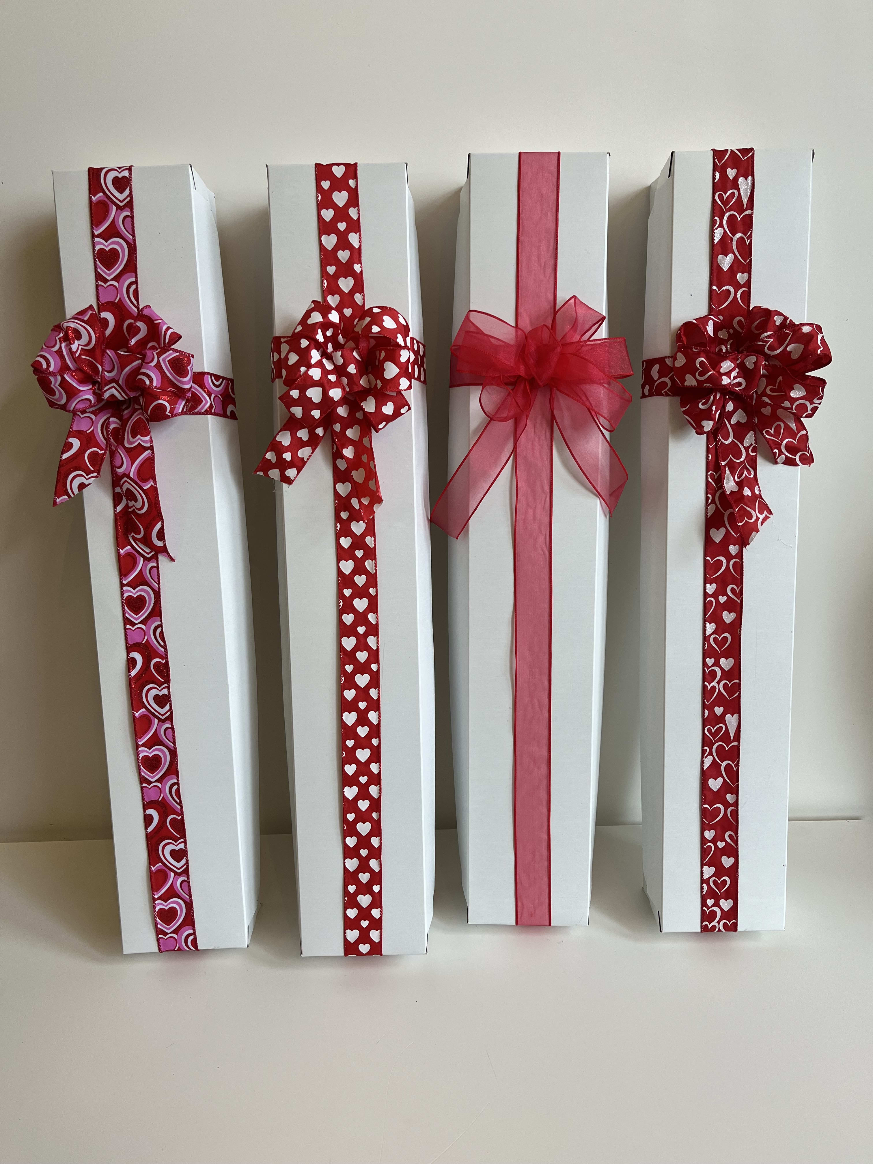 Four white gift boxes decorated with red heart ribbons and bows