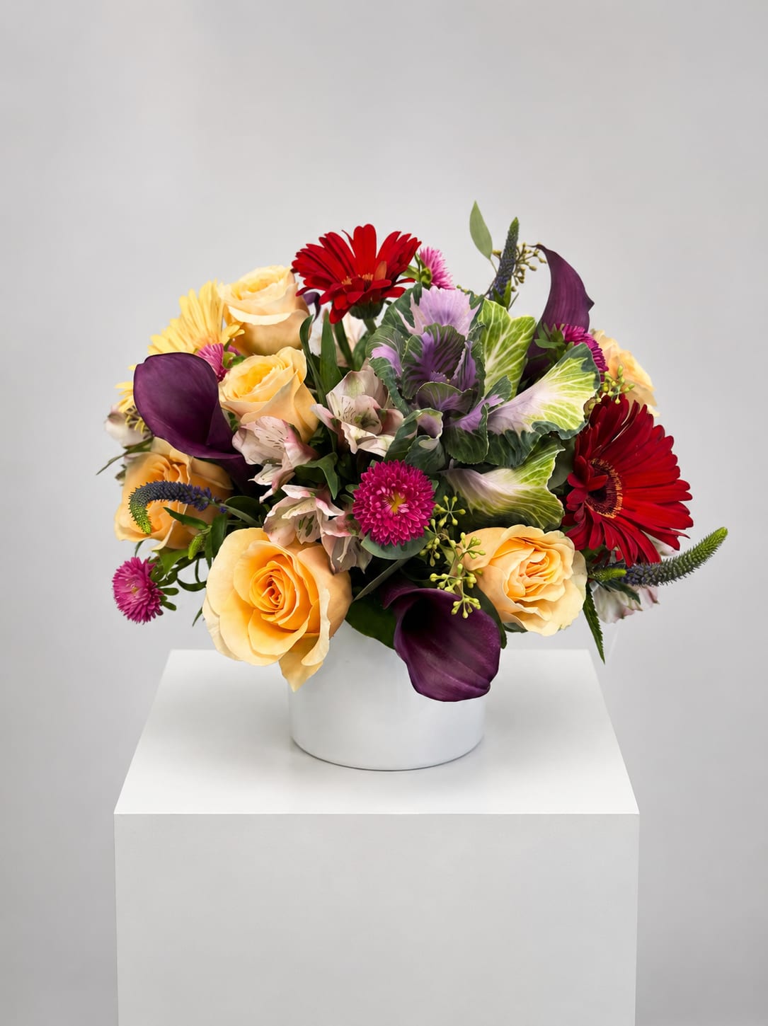 Mixed bouquet in a white vase with yellow roses, red gerberas, and purple calla lilies