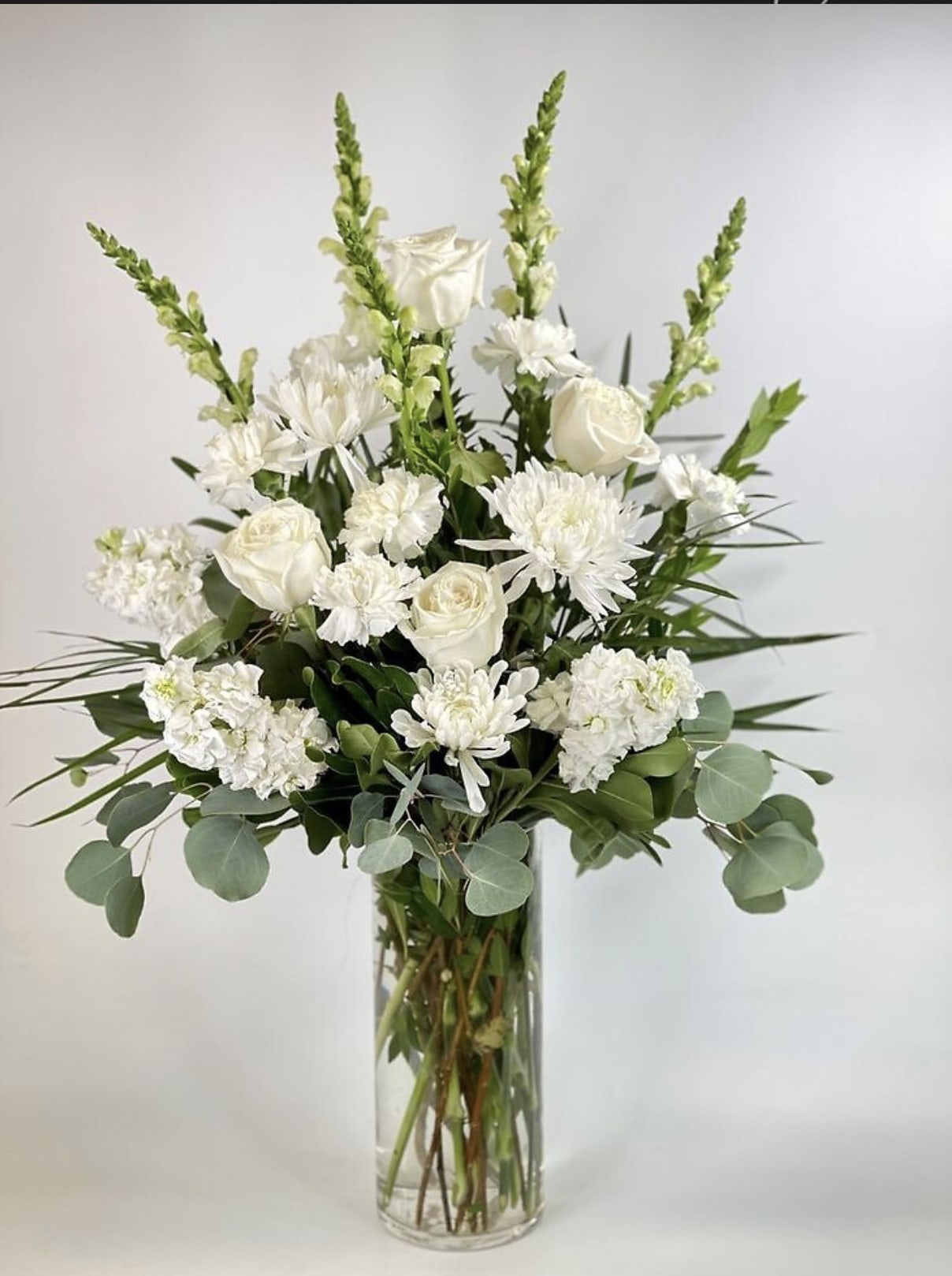White roses and chrysanthemums in a clear glass vase